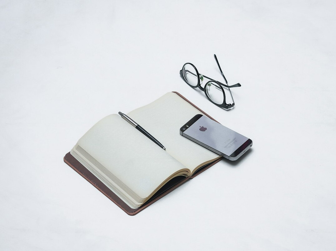 Old typewriter with a detective notebook and magnifying glass on a wooden desk